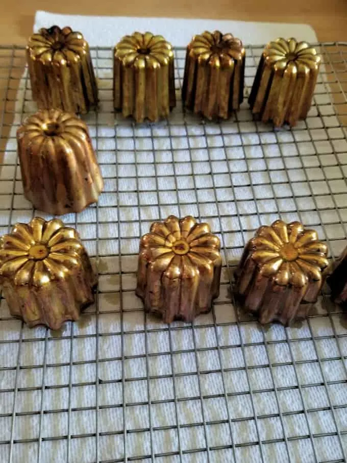 canele molds draining on a baking rack