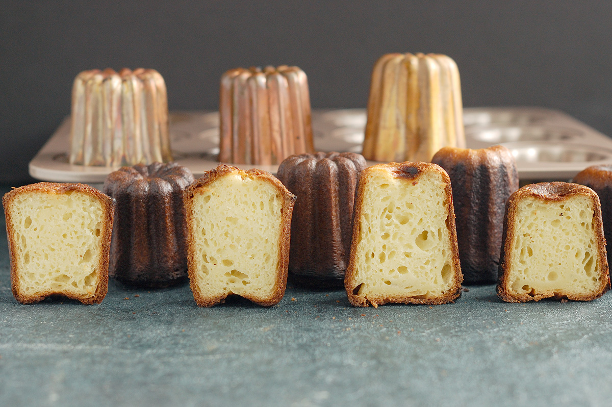 four different canele molds with 4 caneles lined up as comparison.