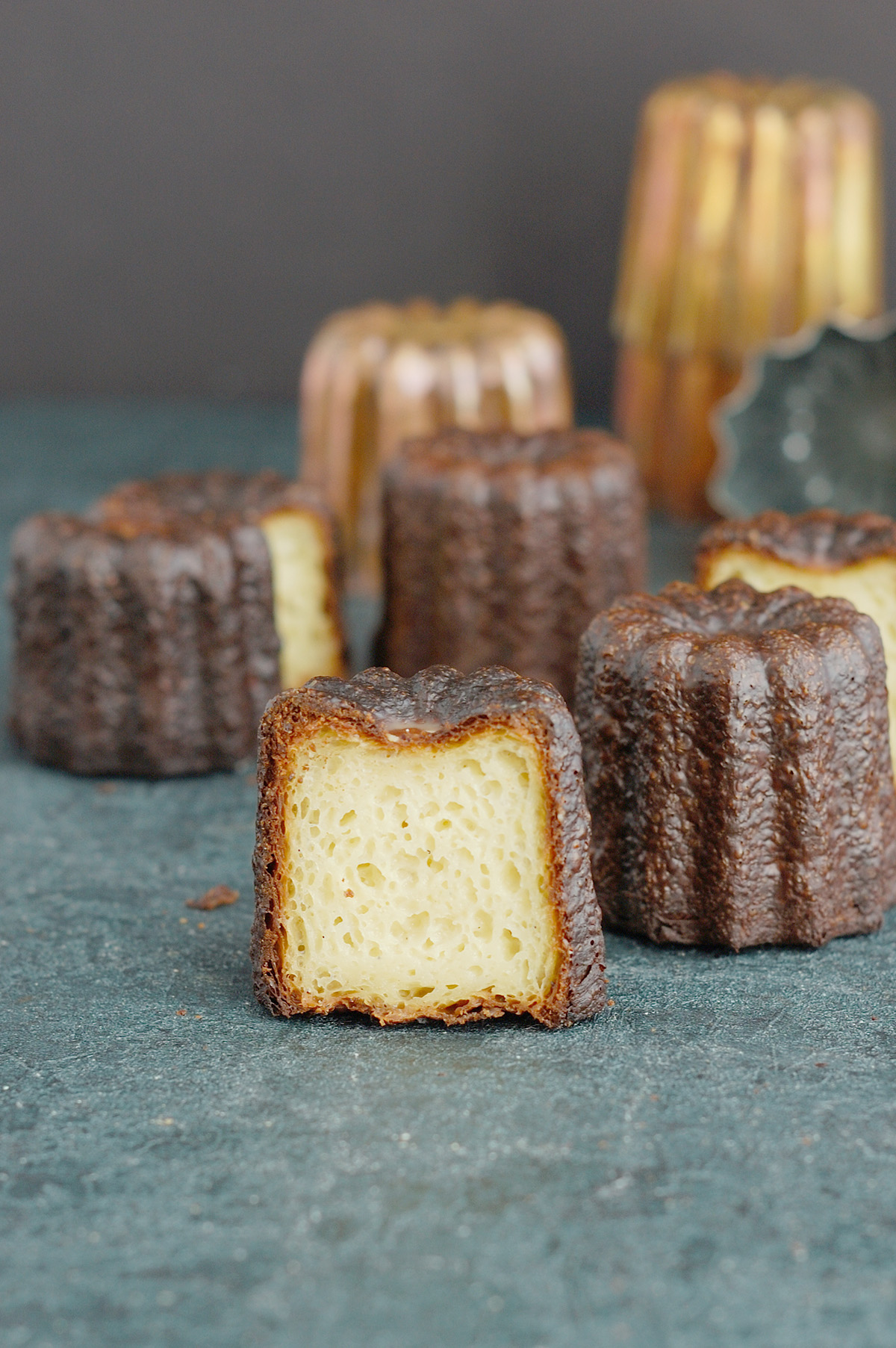 a split canele with overly black crust on a black surface.