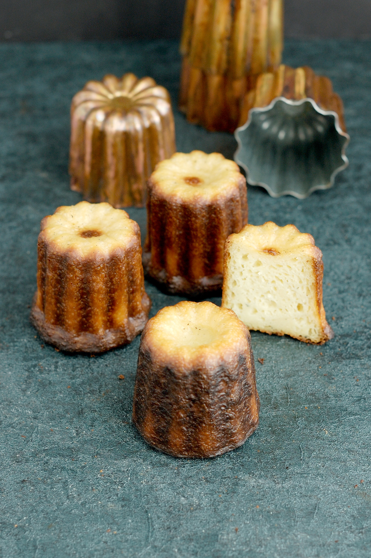 four caneles on a black surface.