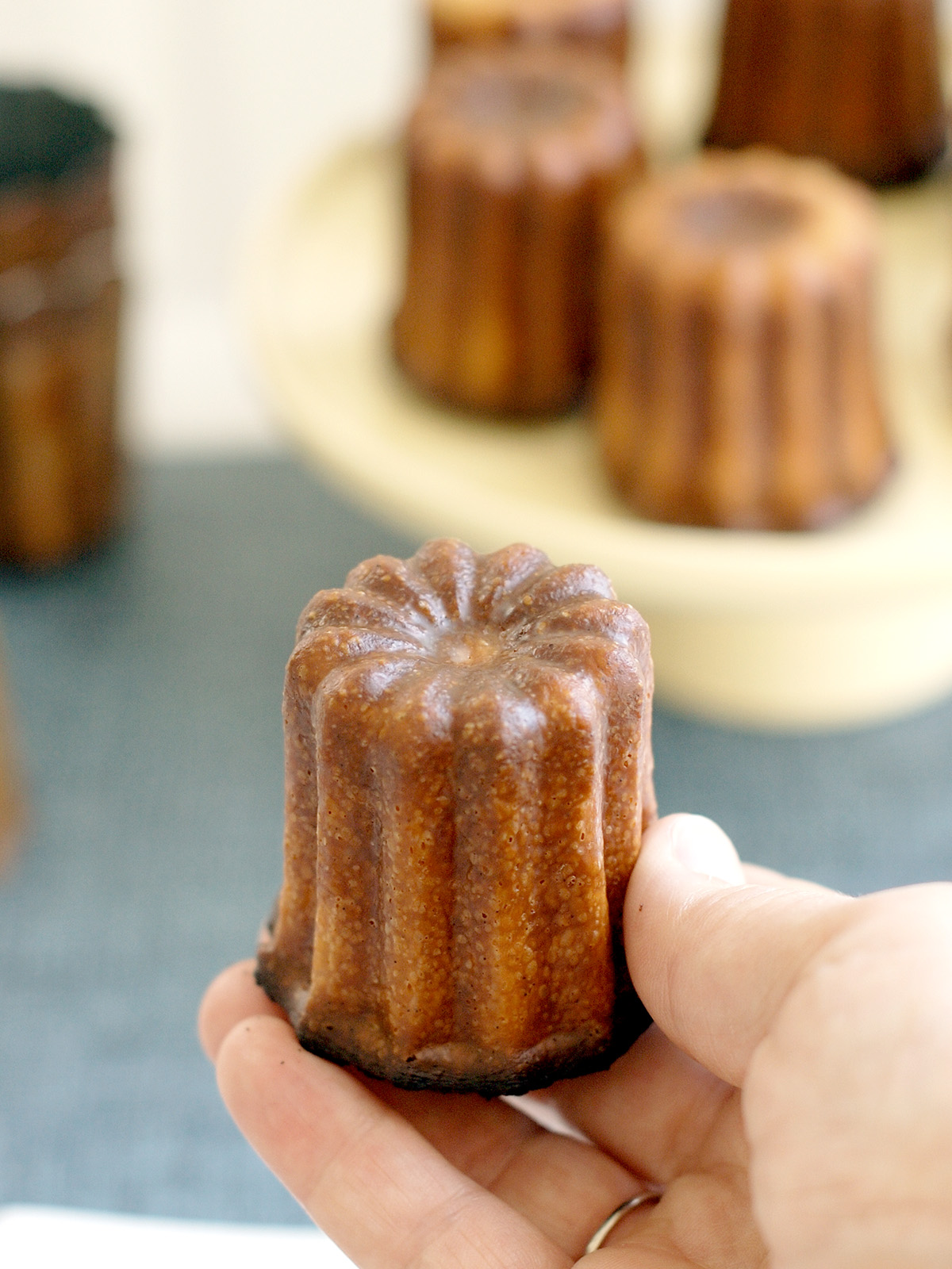 a hand holding a perfect french canele
