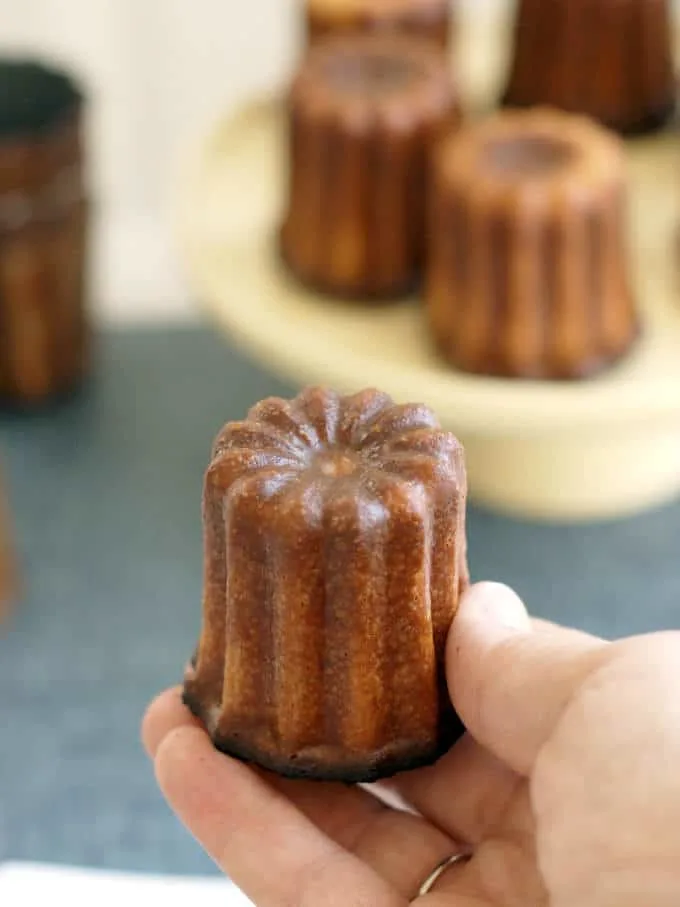 a hand holding a french canele
