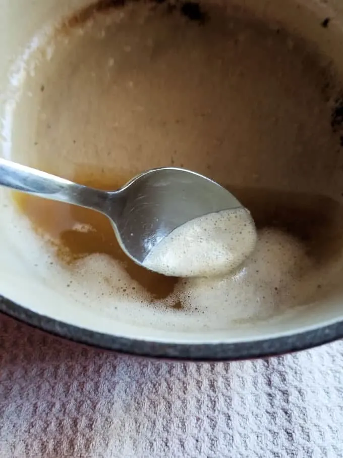 a spoon skimming foam for clarified butter