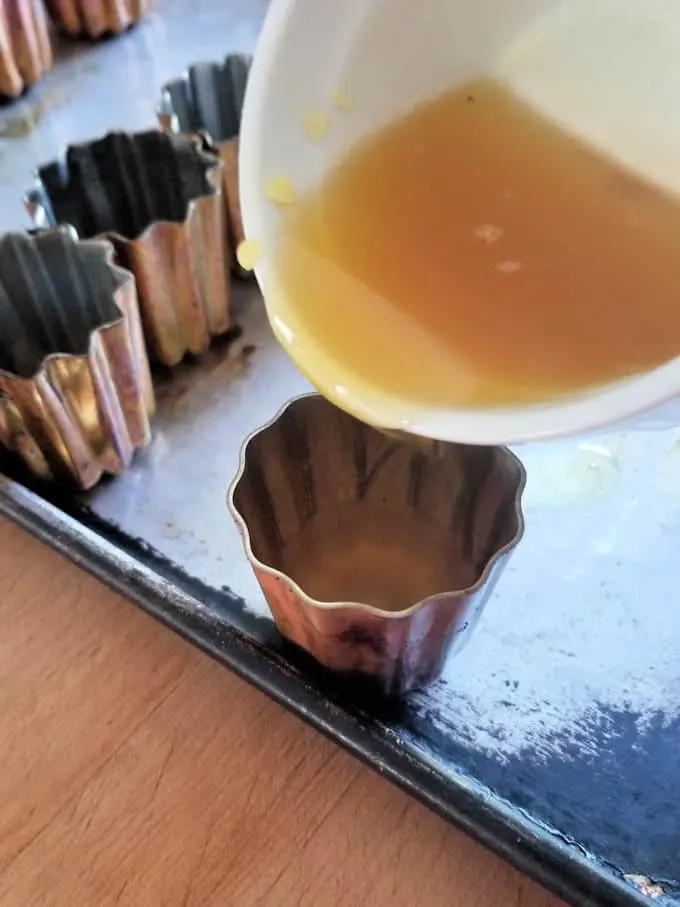 pouring melted bees wax into a canele mold