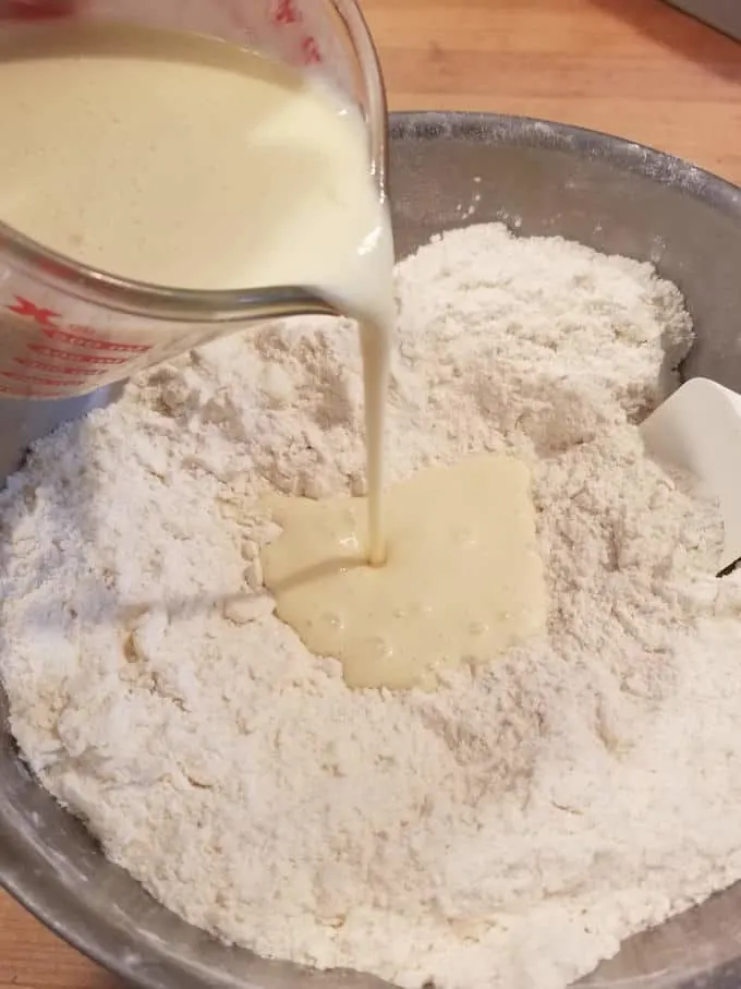 buttermilk and sourdough discard being poured into a bowl of flour