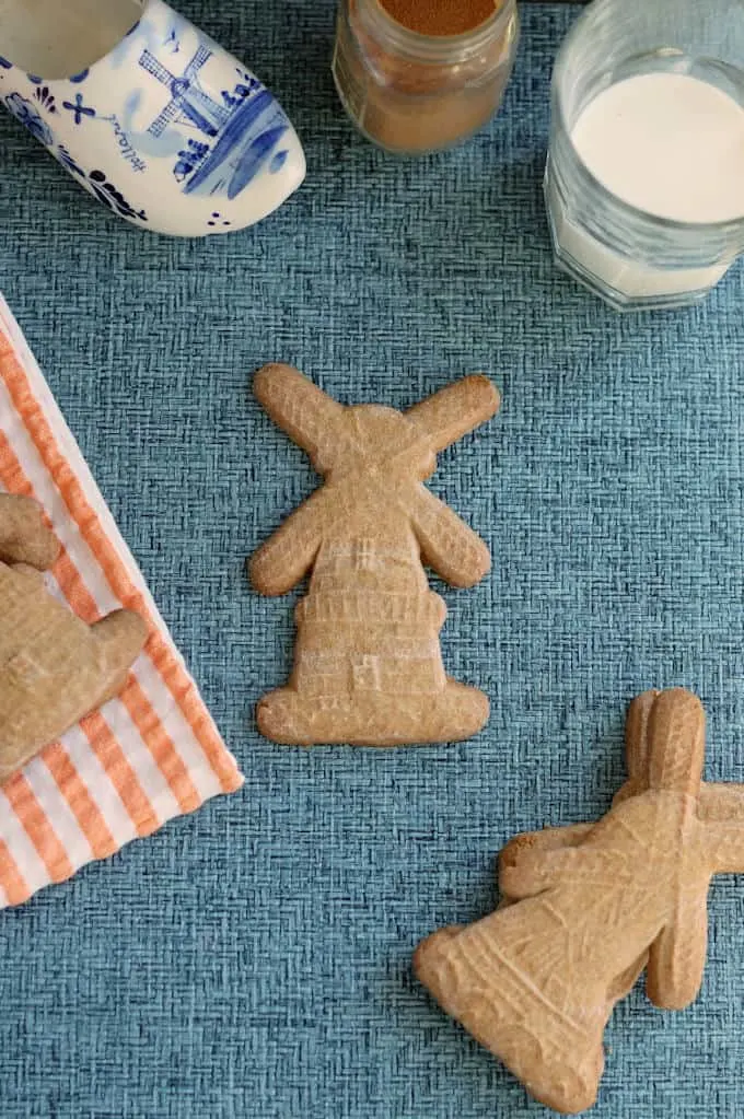 a blue surface with speculaas cookies, a glass of milk, spices and decorations