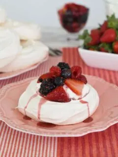 a pavlova with berries and cream on a pink plate