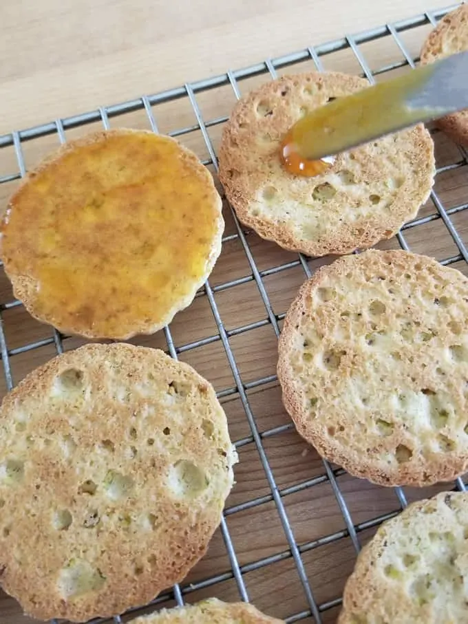 spreading apricot preserves on the flat side of a pistachio cookie