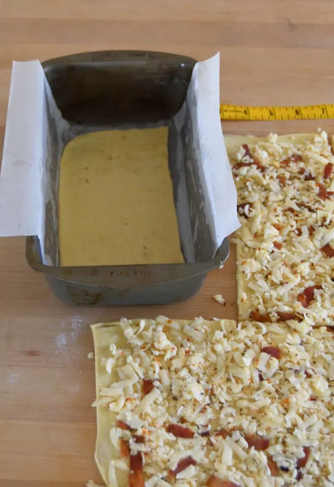 bread dough topped with bacon and pepper jack, ready to layer into a loaf pan.