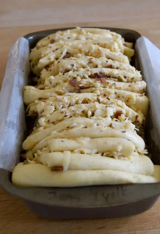 bacon and pepper jack filling layered with bread dough in a loaf pan