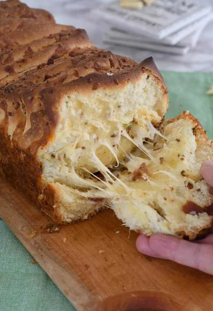 a hand pulling off a slice of bacon and pepper jack pull apart bread