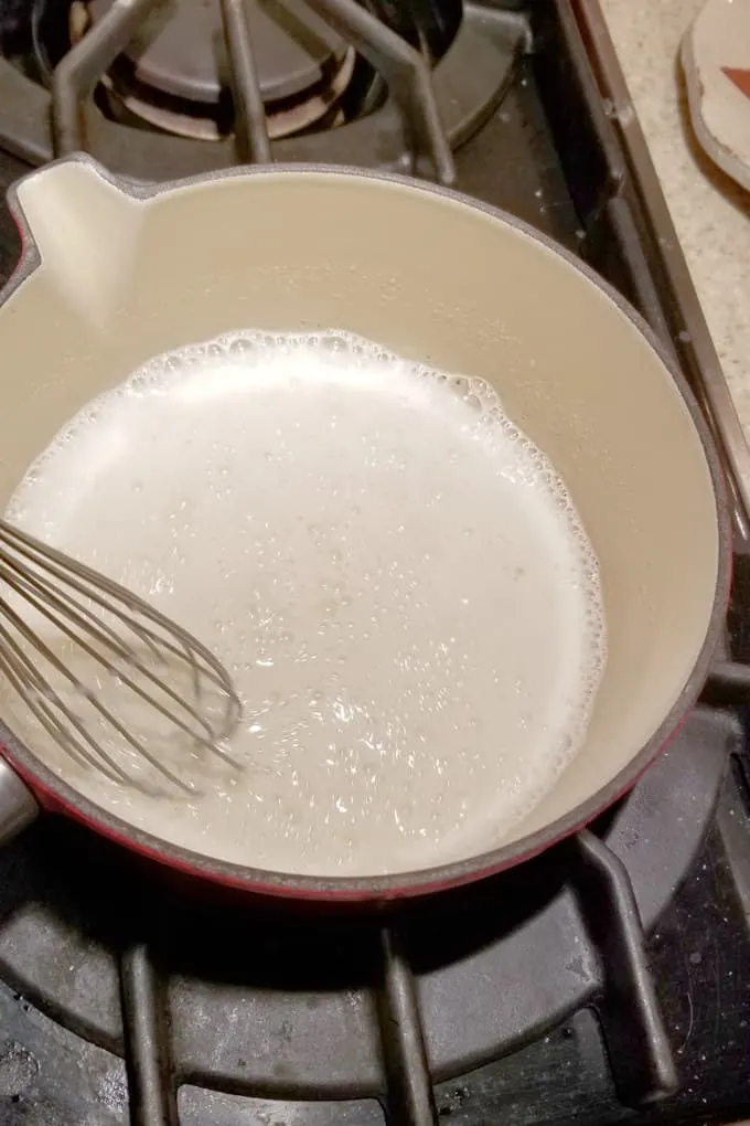 milk and flour being whisked together in a small pot