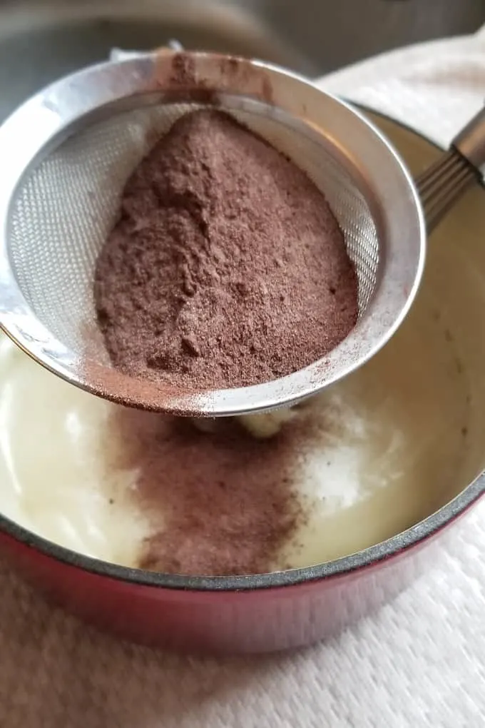 cocoa powder and malted milk powder being sifted into a milk base