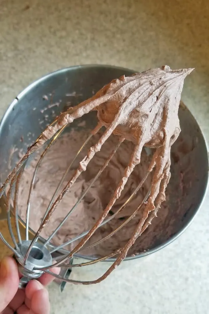 a whisk showing whipped malted chocolate frosting
