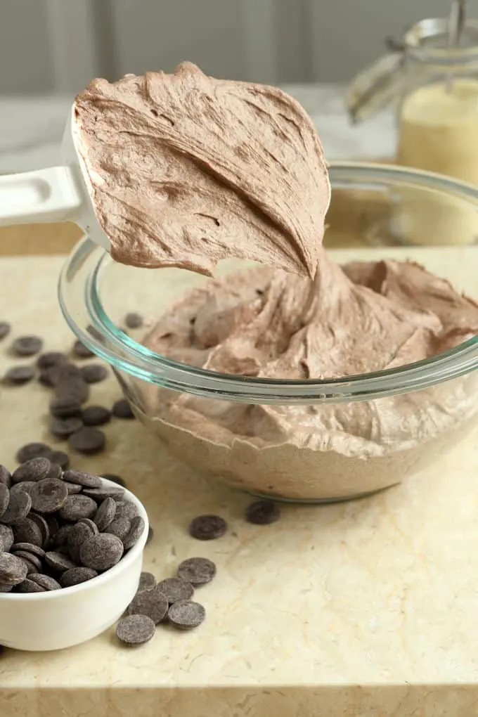 a spatula scooping out malted chocolate frosting from a bowl