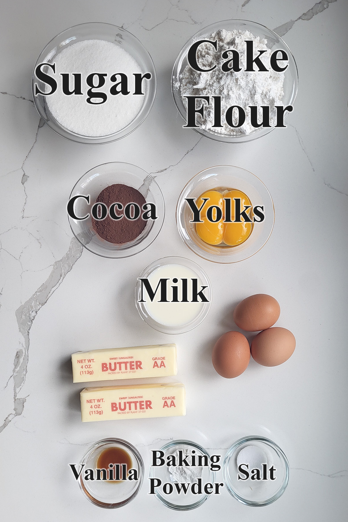 ingredients for marble pound cake in glass bowls on a white surface.