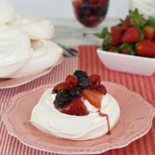 a pavlova with berries and cream on a pink plate