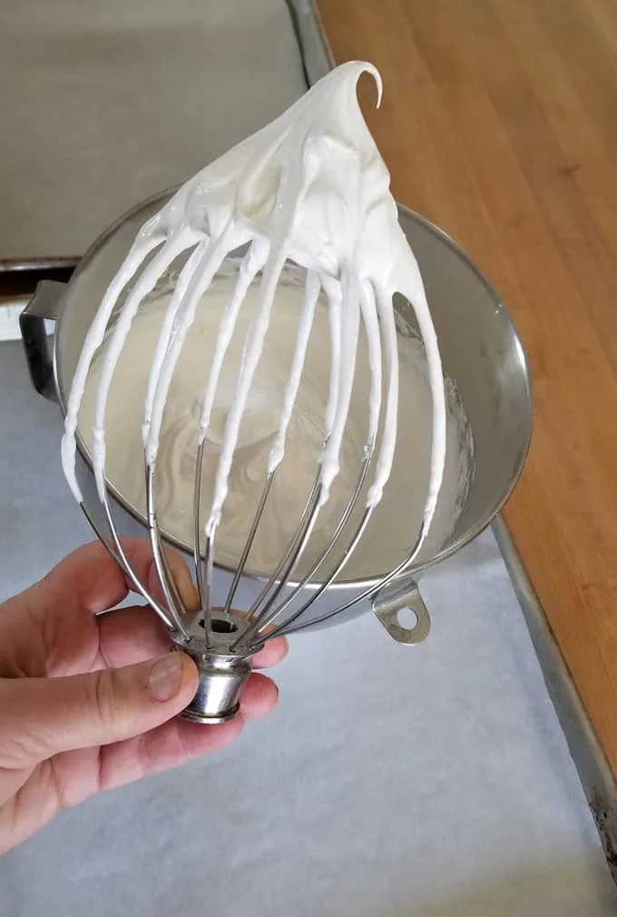 a whisk showing egg whites whipped to stiff peak