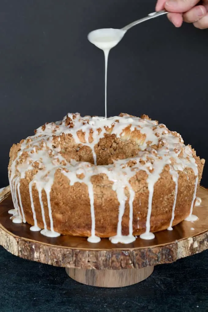 a spoon drizzling icing on a sourdough coffee cake