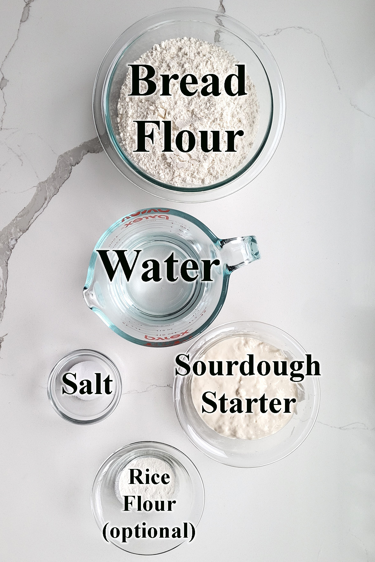 ingredients for sourdough bread in glass bowls on a white surface.