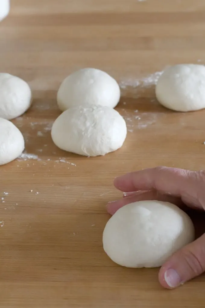 a hand shaping a piece of sourdough into a ball