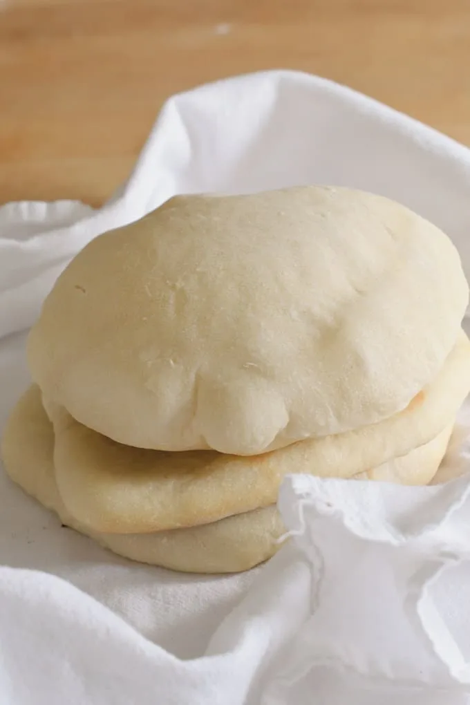 a stack of warm sourdough pita bread wrapped in a kitchen towel