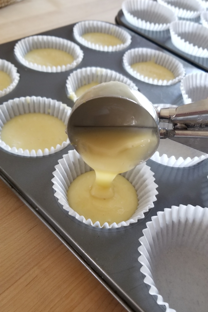 a scooper putting batter into a cupcake pan.