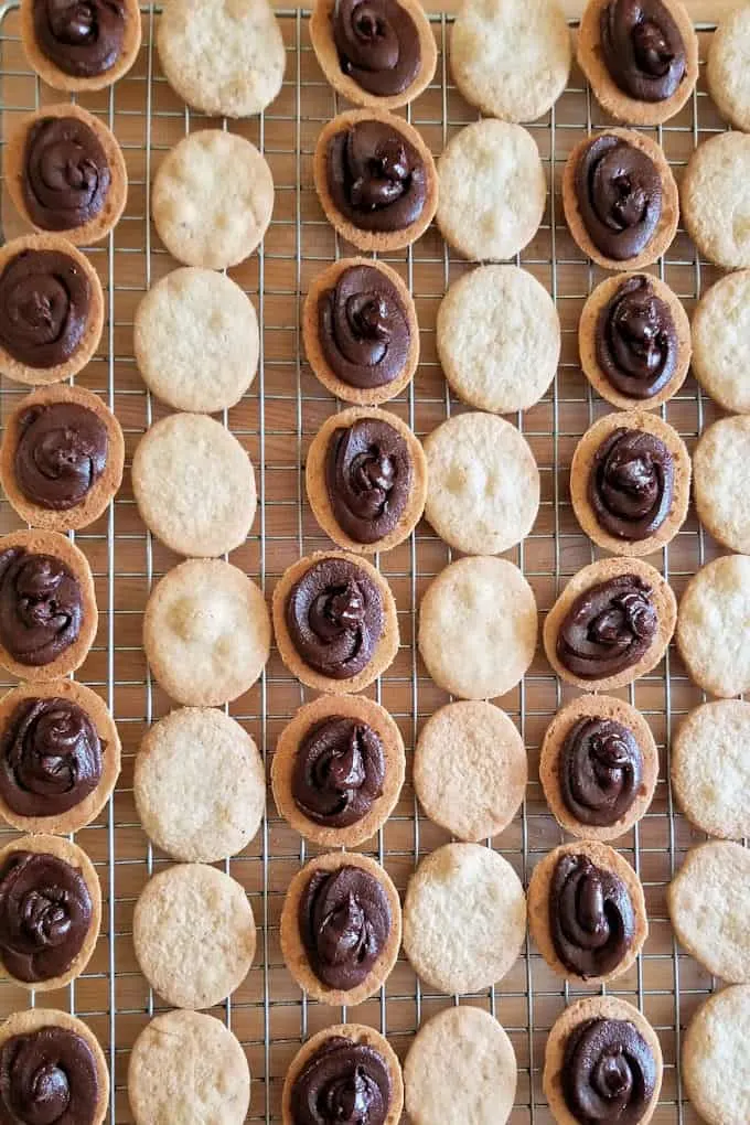 a cooling rack filled with hazelnut cookies ready to sandwich together with chocolate filling