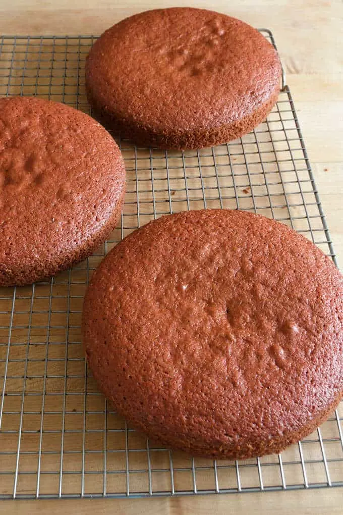 three layers of red velvet cake cooling on a rack