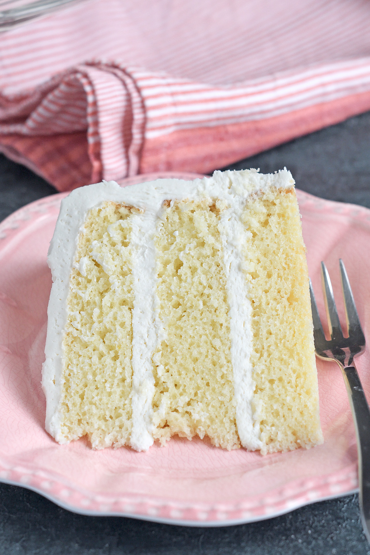 a slice of vanilla buttermilk cake on a pink plate.