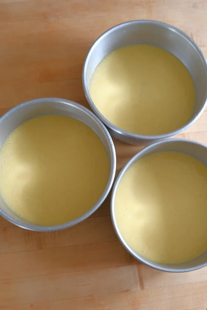 three cake pans filled with vanilla buttermilk cake batter