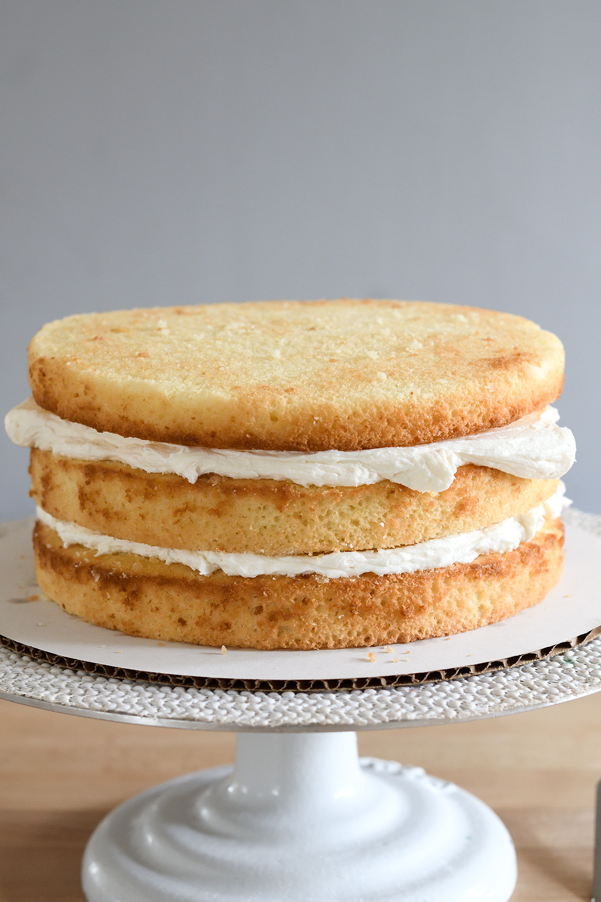 a three layer vanilla buttermilk cake with filling on a cake turntable.