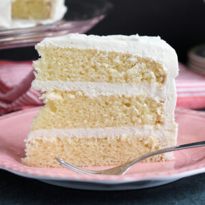 a slice of vanilla buttermilk cake standing on a pink plate with a fork.