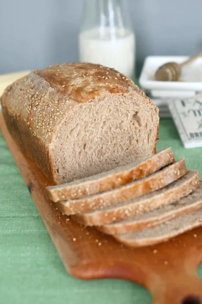 a slices loaf of whole wheat sourdough bread on a cutting board