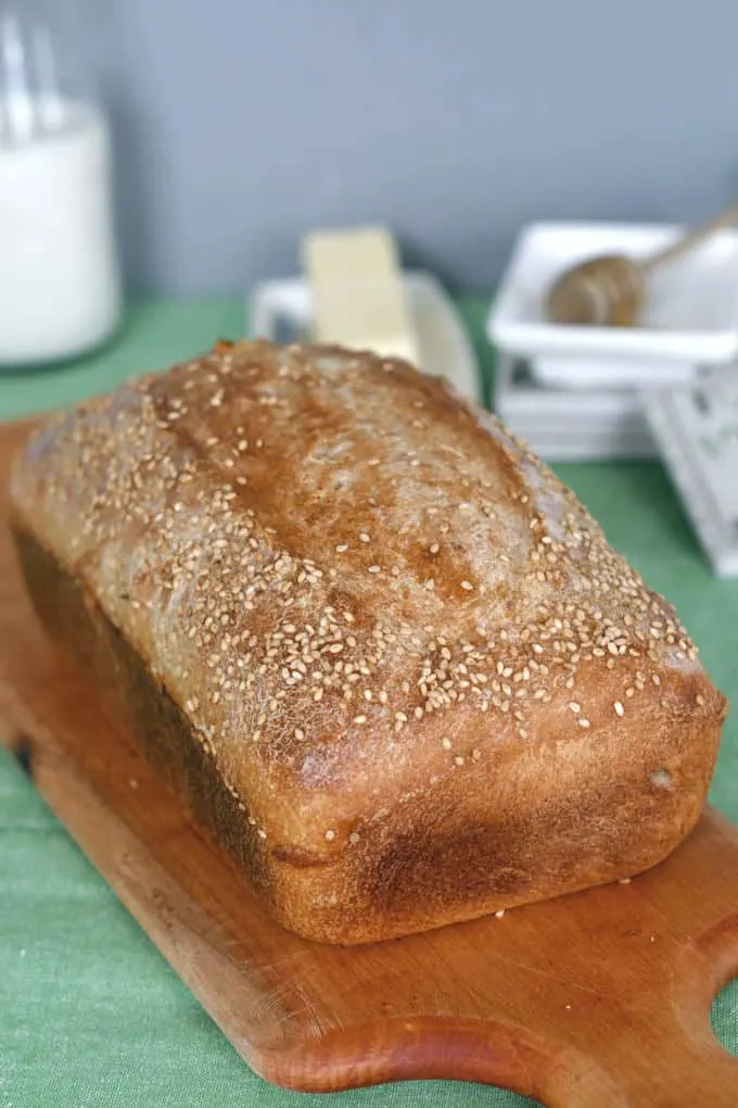 a freshly baked loaf of sourdough whole wheat sandwich bread on a cutting board
