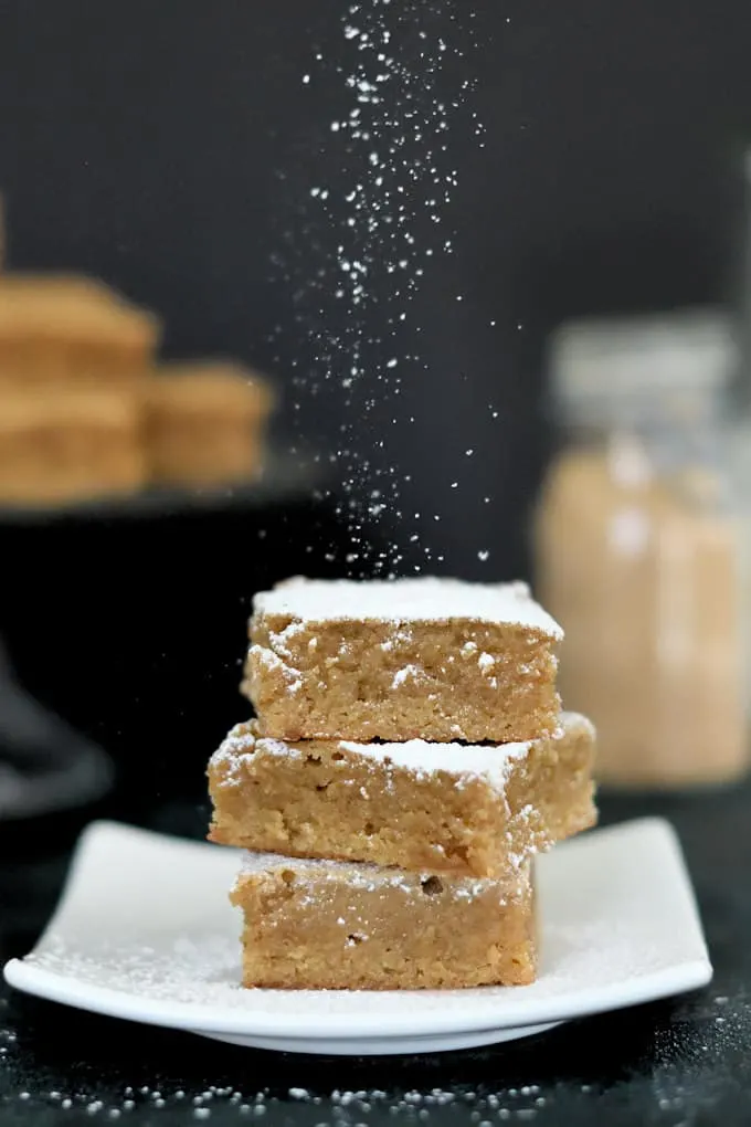 a stack of three blondies being sprinkled with powdered sugar