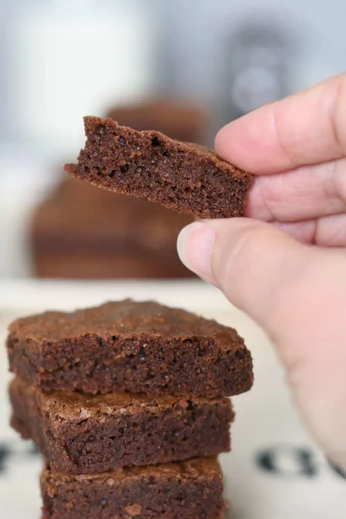 a hand holding a piece of a fudgy brownie