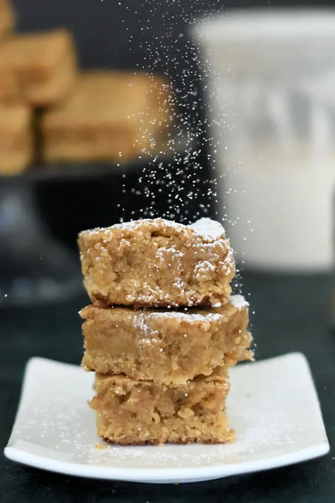three butterscotch blondies on a plate sprinkled with sugar