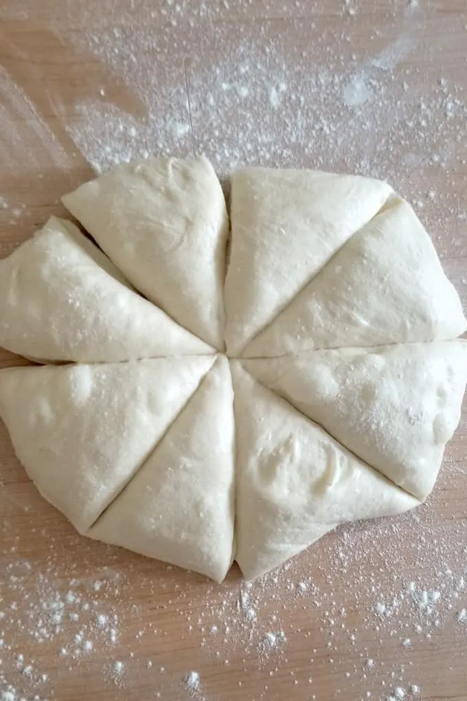 a slab of sourdough hamburger bun dough divided into 8 equal pieces.