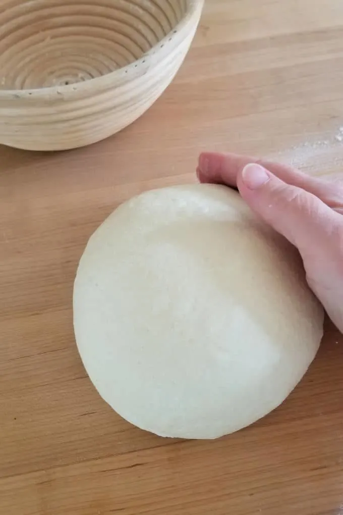 a hand forming a bread boule