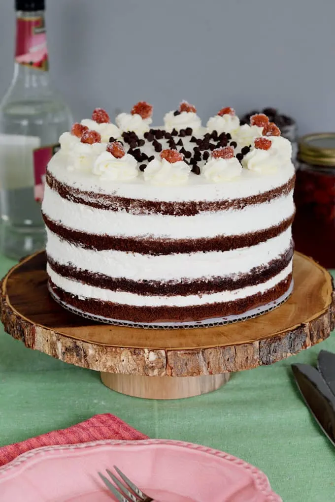 A black forest layer cake set on a wooden cake stand. 