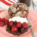 a chocolate shortcakes biscuit topped with raspberries and blackberries and whipped cream