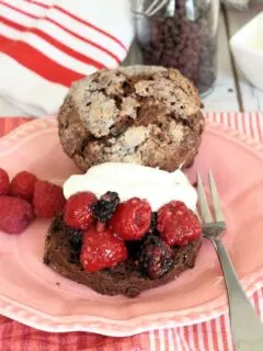 a chocolate shortcakes biscuit topped with raspberries and blackberries and whipped cream