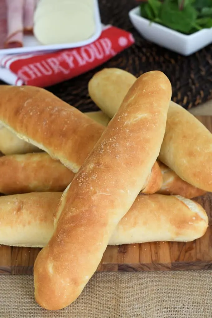 hoagie rolls stacked on a cutting board