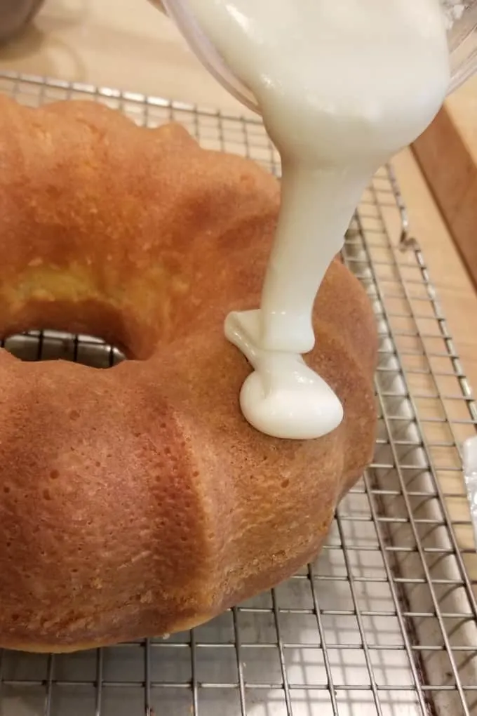 a closeup shot showing glaze being poured onto a slightly warm bundt cake