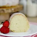 a slice of sourdough bundt cake on a plate with a few strawberries