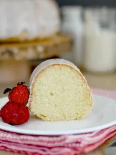 a slice of sourdough bundt cake on a plate with a few strawberries