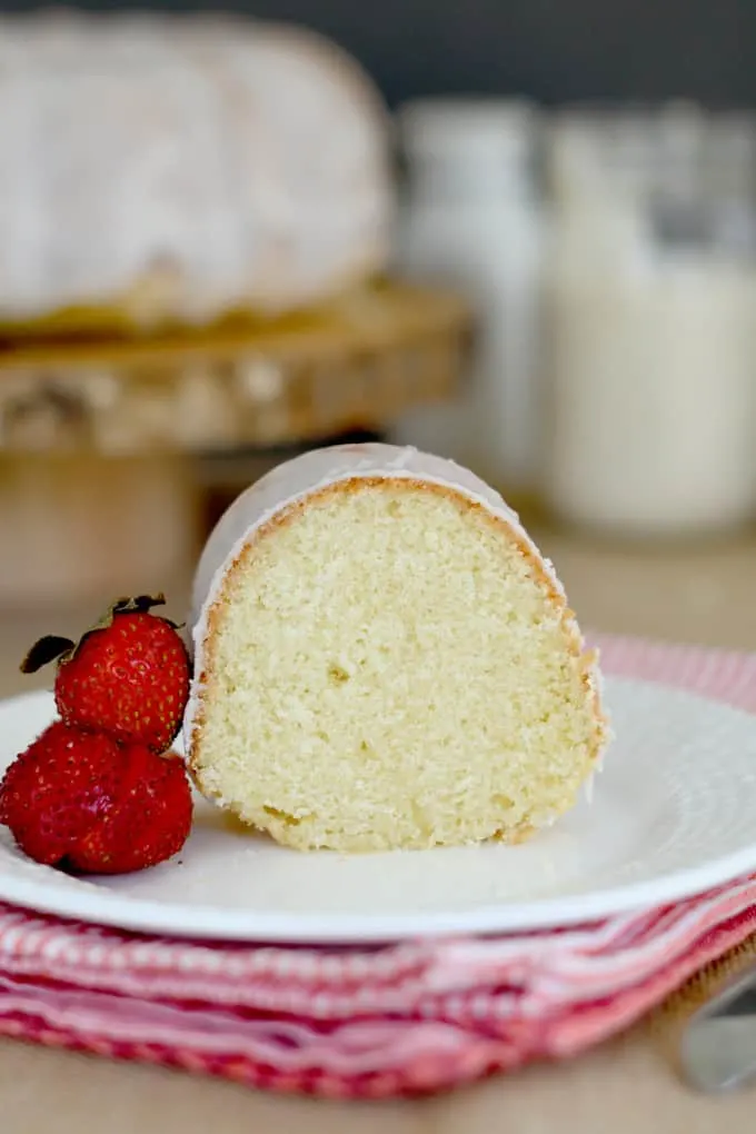 a slice of sourdough bundt cake on a plate with a few strawberries
