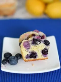 a lemon blueberry muffin cut in half on a plate