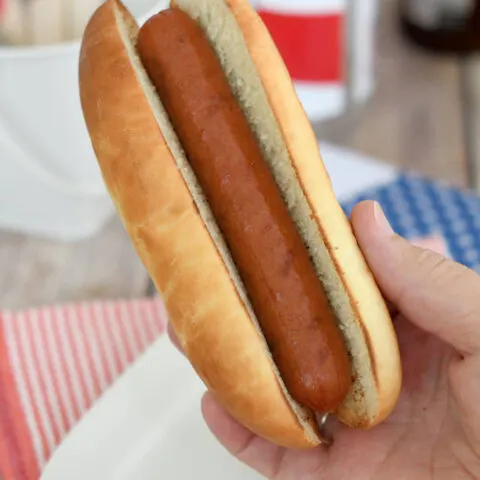 a hand holding a hot dog in a homemade bun